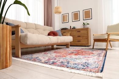 Photo of Beautiful rug, sofa, armchair and chest of drawers indoors, low angle view