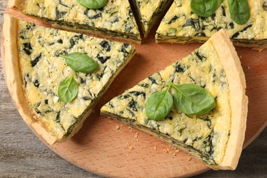 Cut delicious spinach pie on wooden board, top view