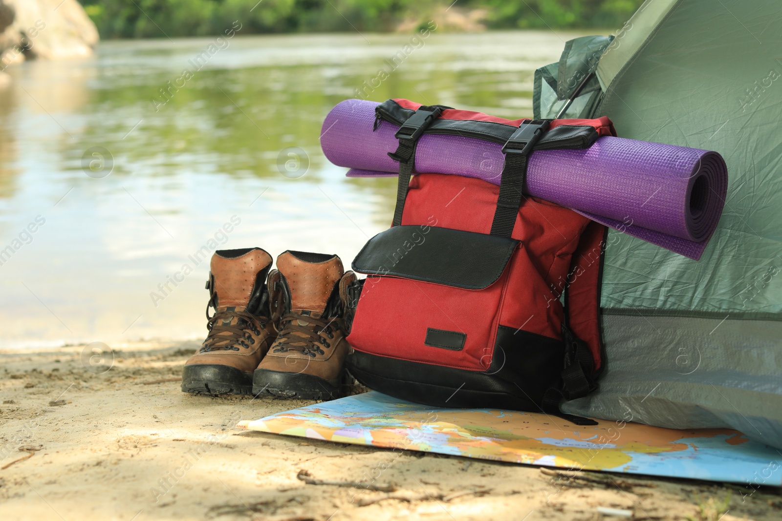 Photo of Modern camping tent and equipment on riverbank. Space for text