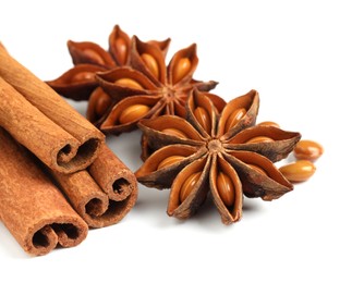 Photo of Dry anise stars and cinnamon sticks on white background, closeup