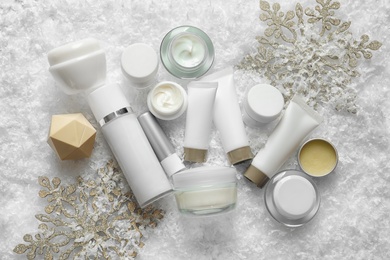 Photo of Set of cosmetic products on decorative snow, flat lay. Winter care