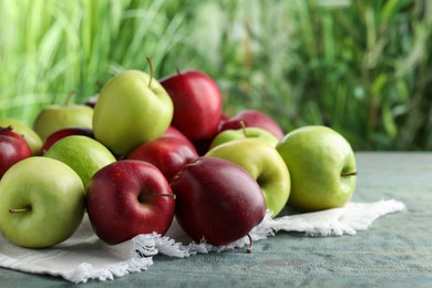 Photo of Fresh ripe red and green apples on light blue wooden table outdoors