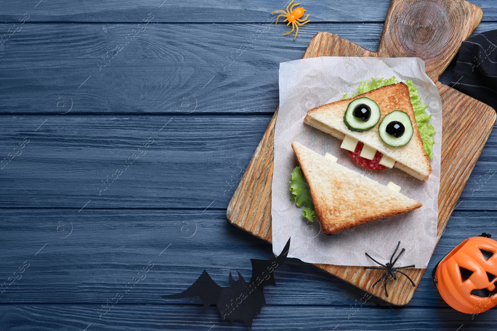 Photo of Cute monster sandwich served on blue wooden table, flat lay with space for text. Halloween party food