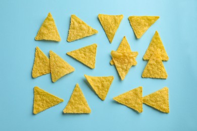 Photo of Flat lay composition of tasty tortilla chips (nachos) on light blue background