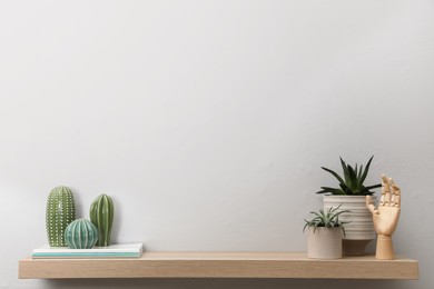 Wooden shelf with beautiful houseplants and stylish interior accessories on white wall. Space for text