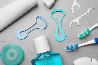 Photo of Flat lay composition with tongue cleaners and teeth care products on grey background