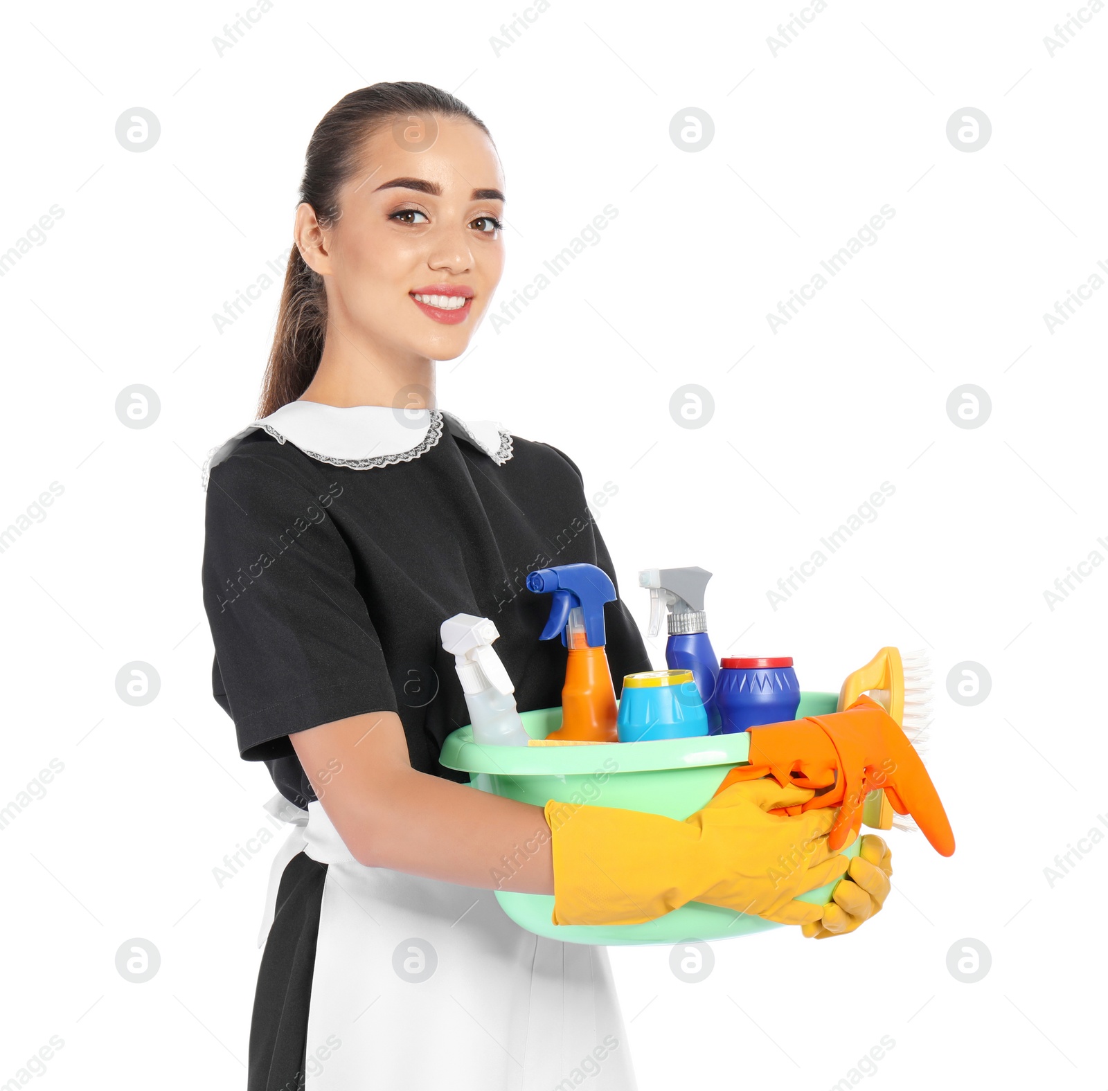 Photo of Young chambermaid holding plastic basin with detergents on white background