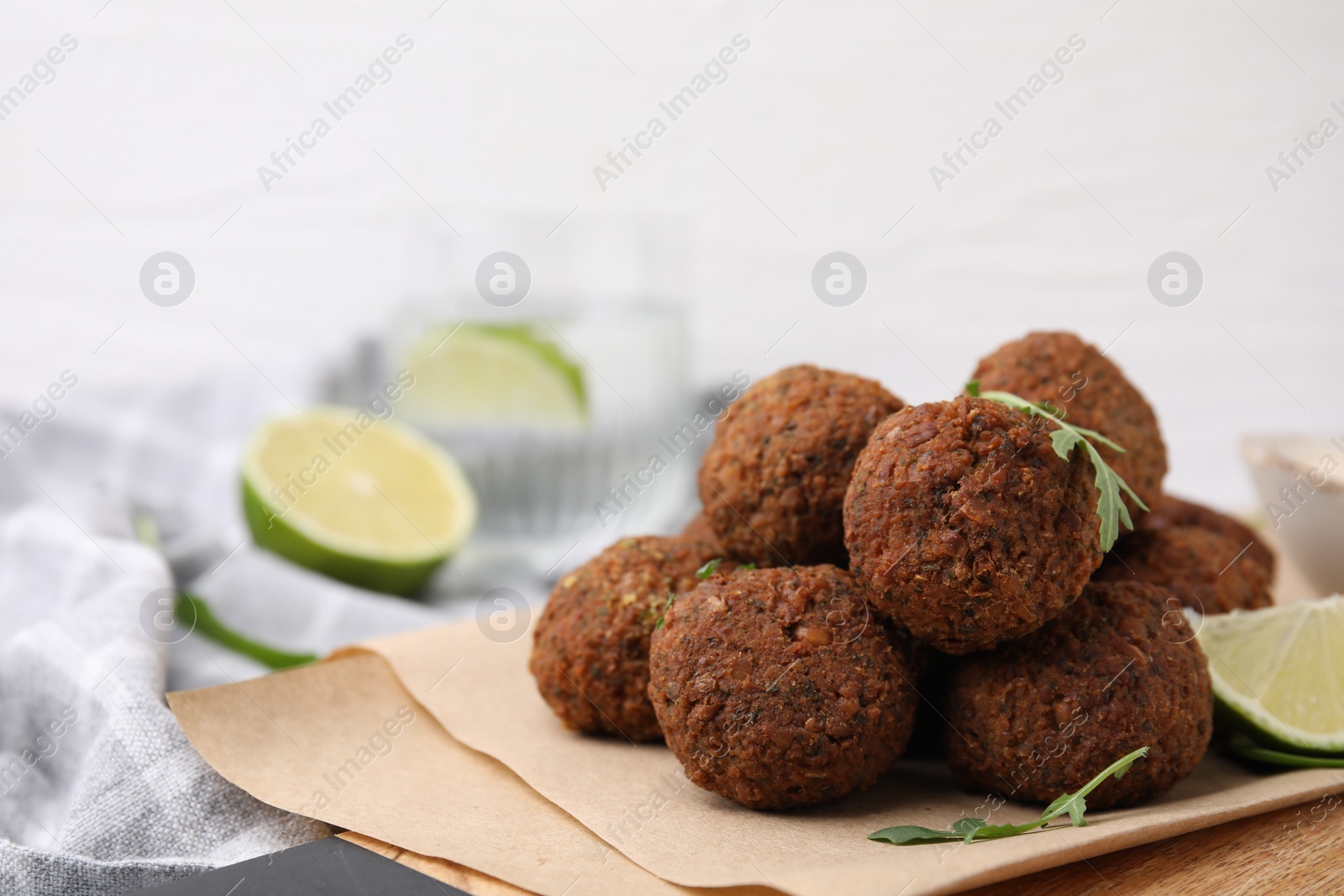 Photo of Delicious falafel balls, arugula and lime on table, closeup. Space for text