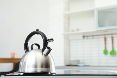 Modern kettle with whistle on stove in kitchen, space for text