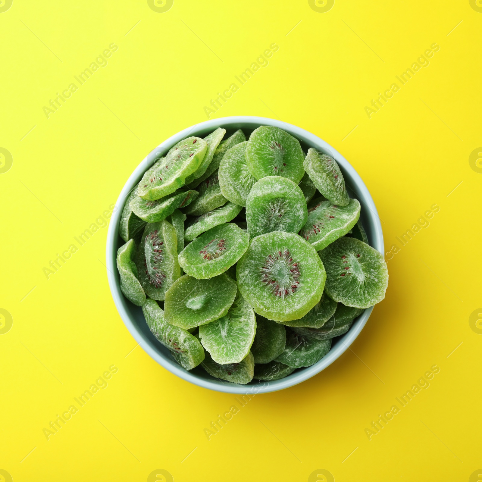 Photo of Bowl with slices of kiwi on color background, top view. Dried fruit as healthy food