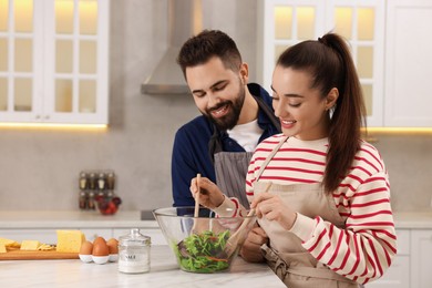 Photo of Happy affectionate couple cooking together at white table in kitchen