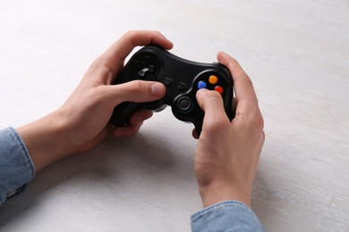 Photo of Man using wireless game controller at white table, closeup