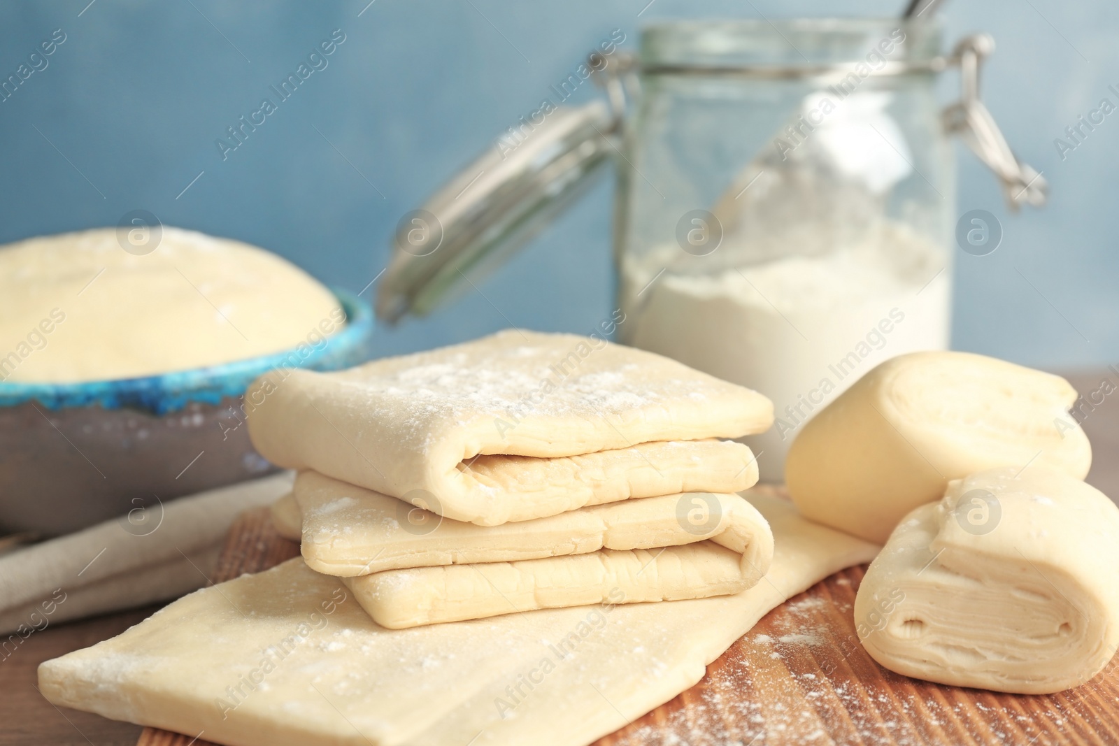 Photo of Fresh raw dough on wooden board, closeup