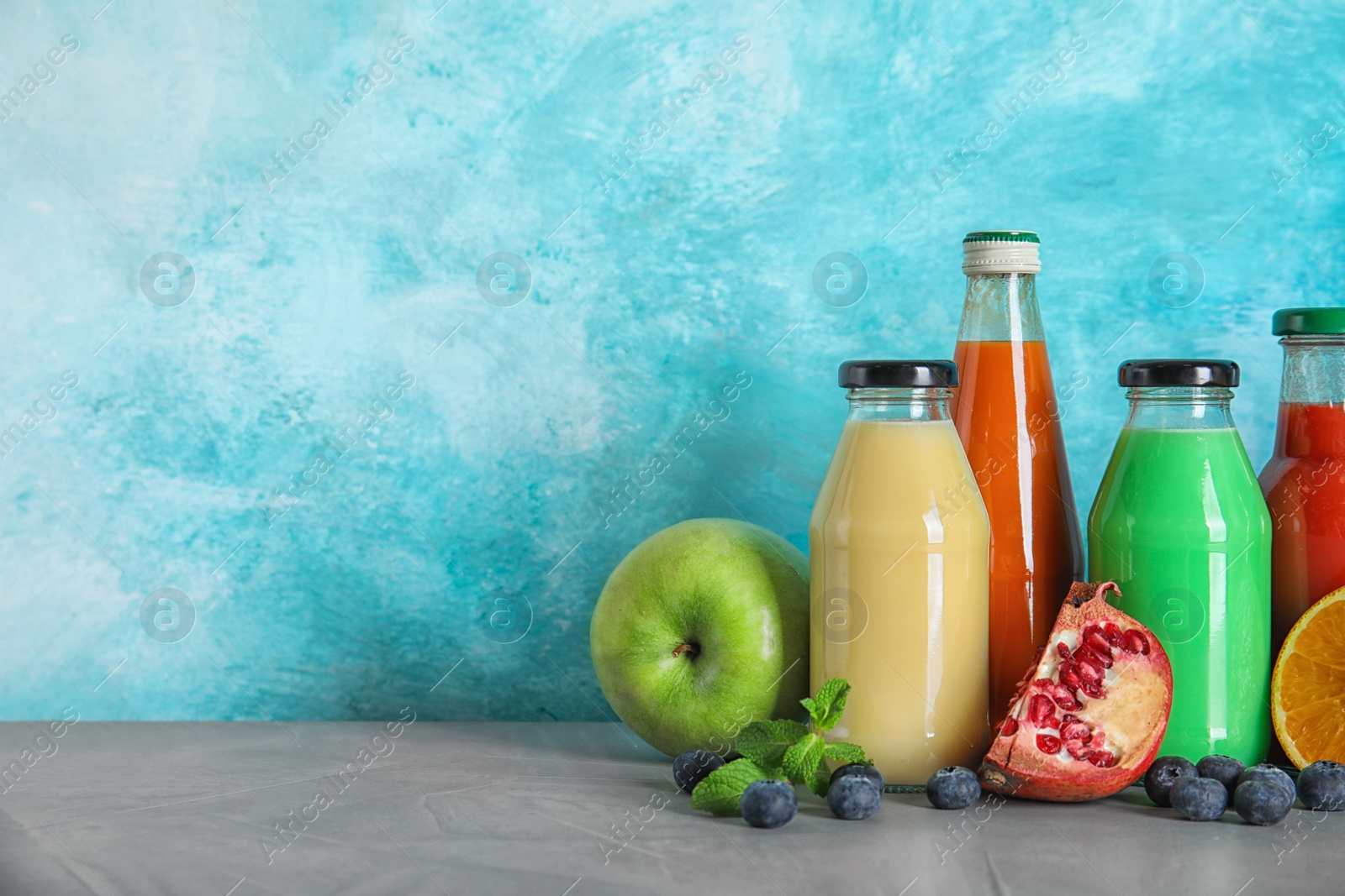 Photo of Bottles with different drinks and ingredients on table against color background. Space for text