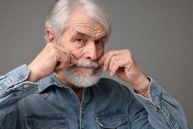 Photo of Senior man touching mustache on grey background