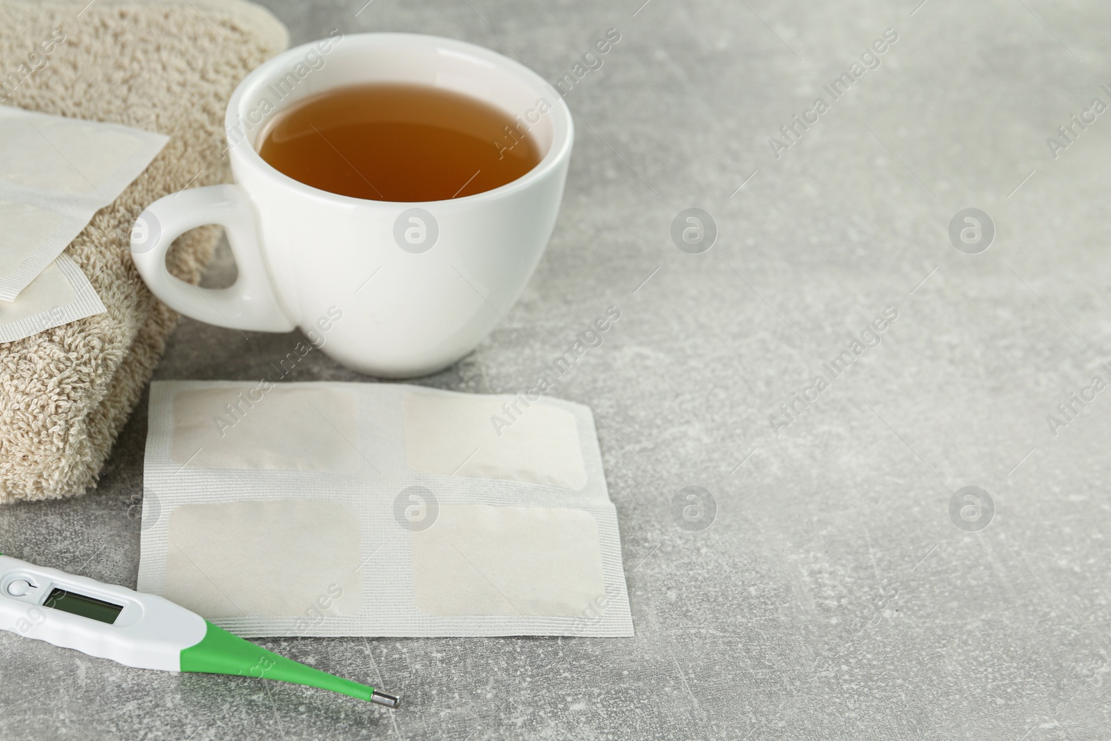 Photo of Mustard plasters, thermometer, towel and tea on light grey table, space for text