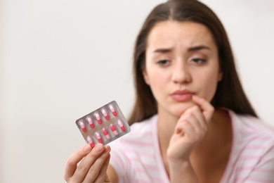 Photo of Young woman with pills on light background, space for text