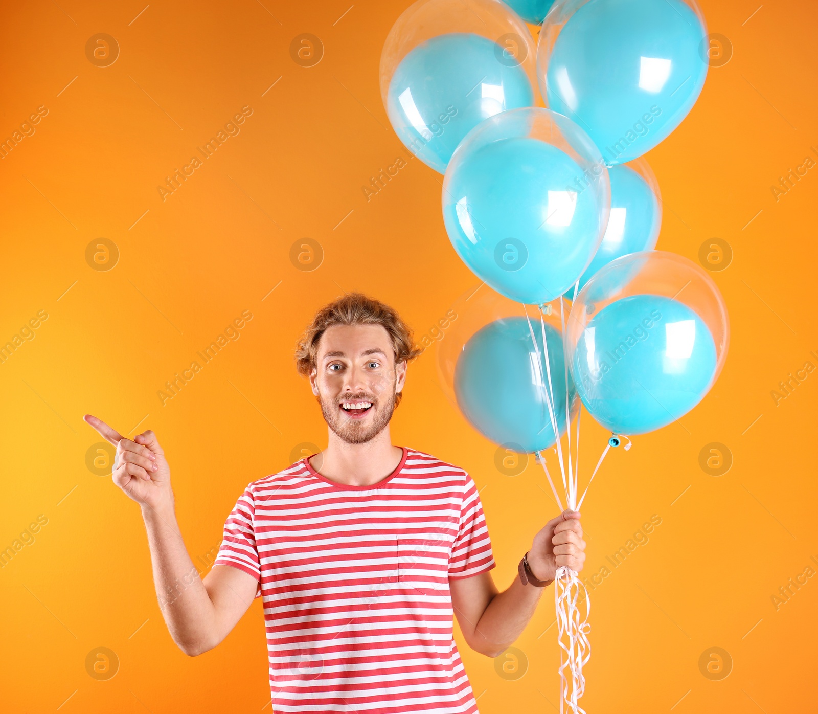 Photo of Young man with air balloons on color background