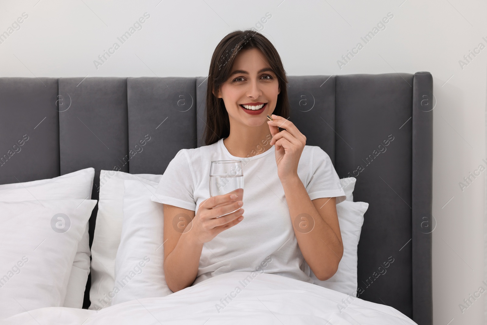 Photo of Beautiful woman taking vitamin pill at home