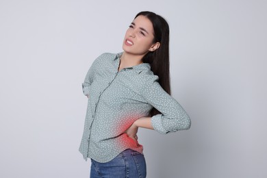 Image of Woman suffering from back pain on light background