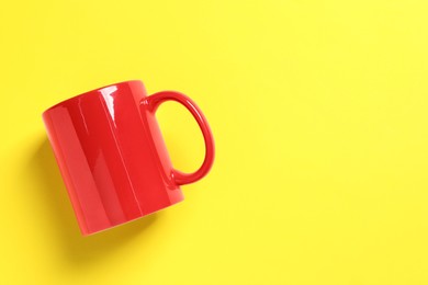 Photo of One red ceramic mug on yellow background, top view. Space for text