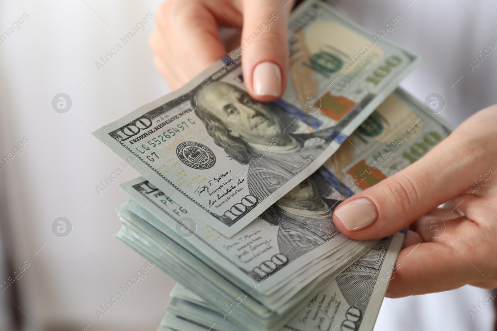 Photo of Money exchange. Woman counting dollar banknotes on blurred background, closeup