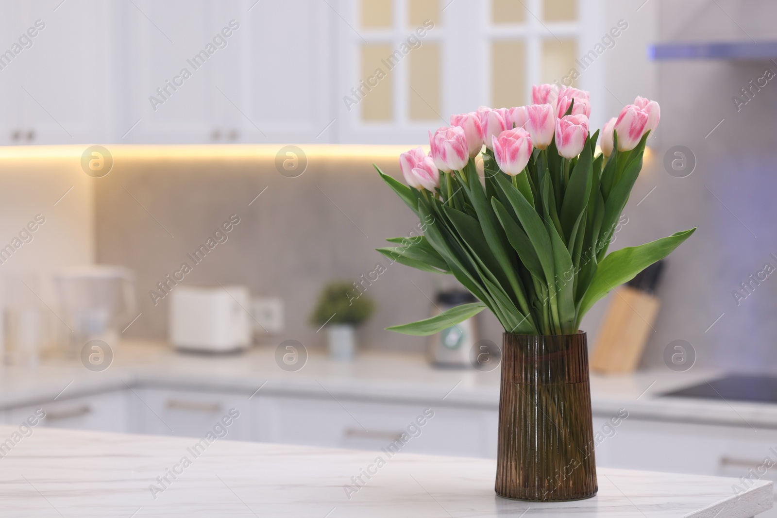 Photo of Beautiful bouquet of fresh pink tulips on table in kitchen. Space for text