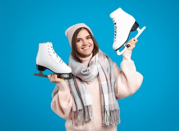 Photo of Happy woman with ice skates on light blue background