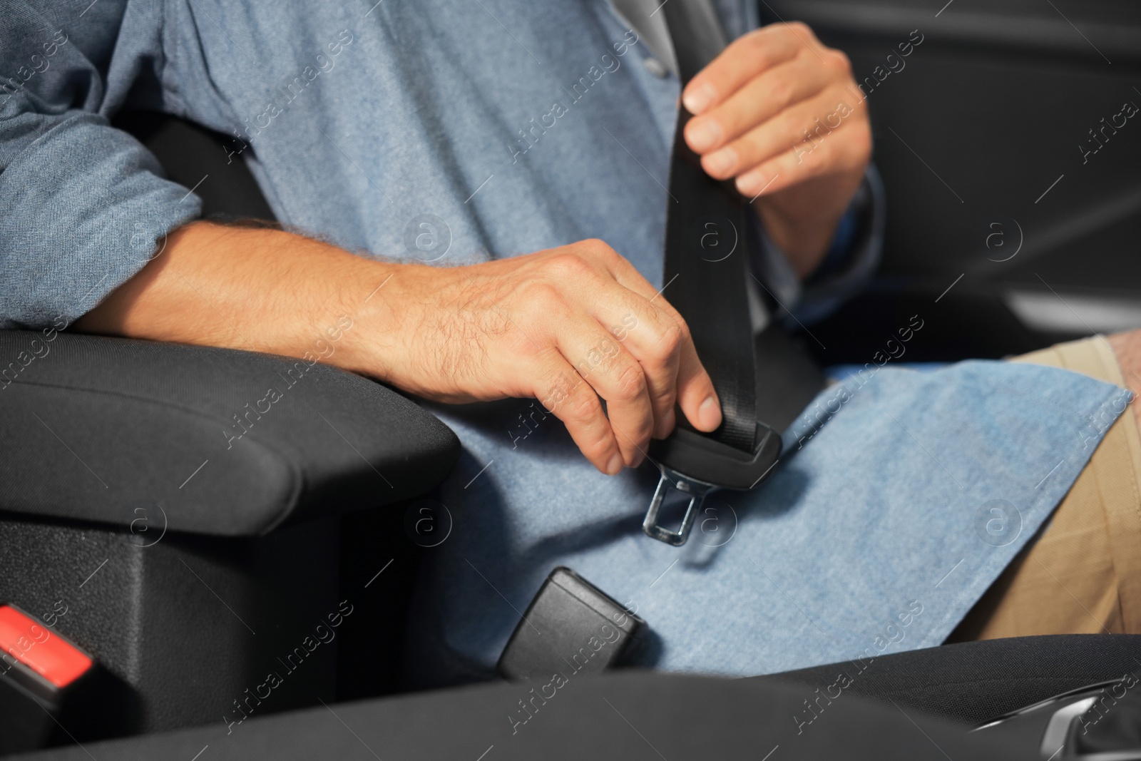 Photo of Man fastening safety seat belt in car, closeup