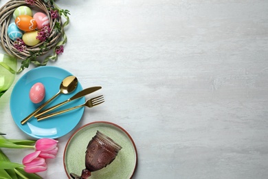 Photo of Festive Easter table setting with painted eggs on wooden background, top view. Space for text