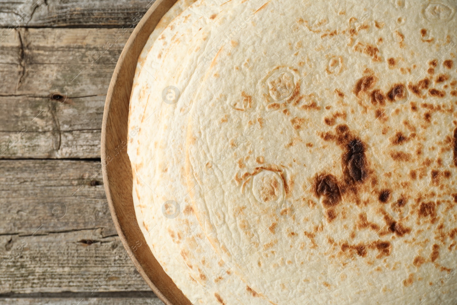 Photo of Stack of tasty homemade tortillas on wooden table, top view