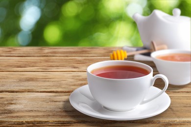 Cup of hot freshly brewed rooibos tea on wooden table outdoors