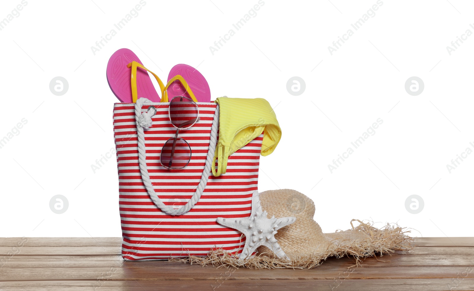 Photo of Stylish bag, starfish and other beach accessories on wooden table against white background