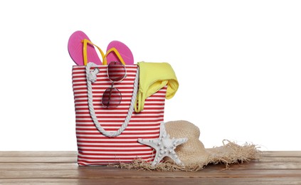 Stylish bag, starfish and other beach accessories on wooden table against white background