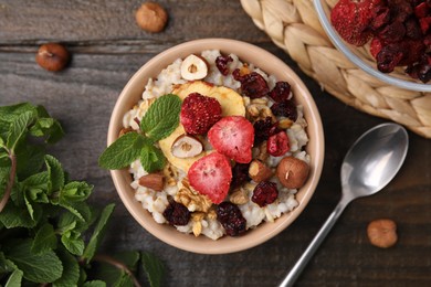 Photo of Oatmeal with freeze dried fruits, nuts and mint on wooden table, flat lay