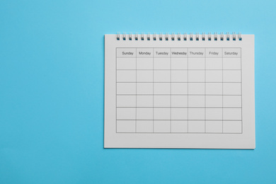 Blank calendar on light blue background, top view. Space for text