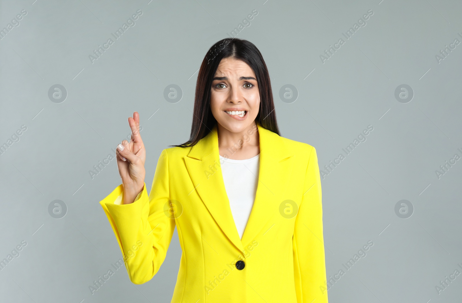 Photo of Woman with crossed fingers on grey background. Superstition concept