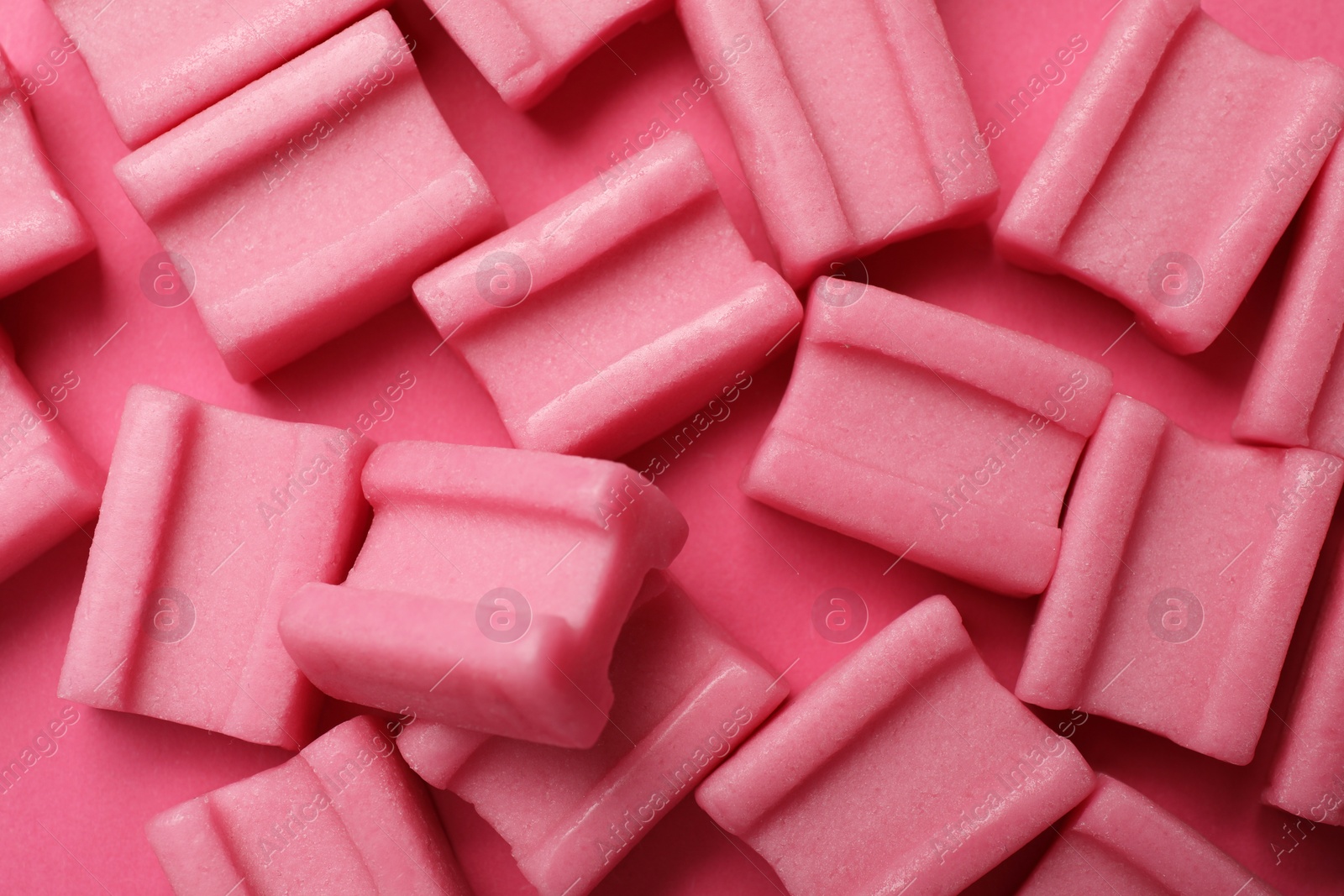 Photo of Tasty chewing gums on pink background, flat lay