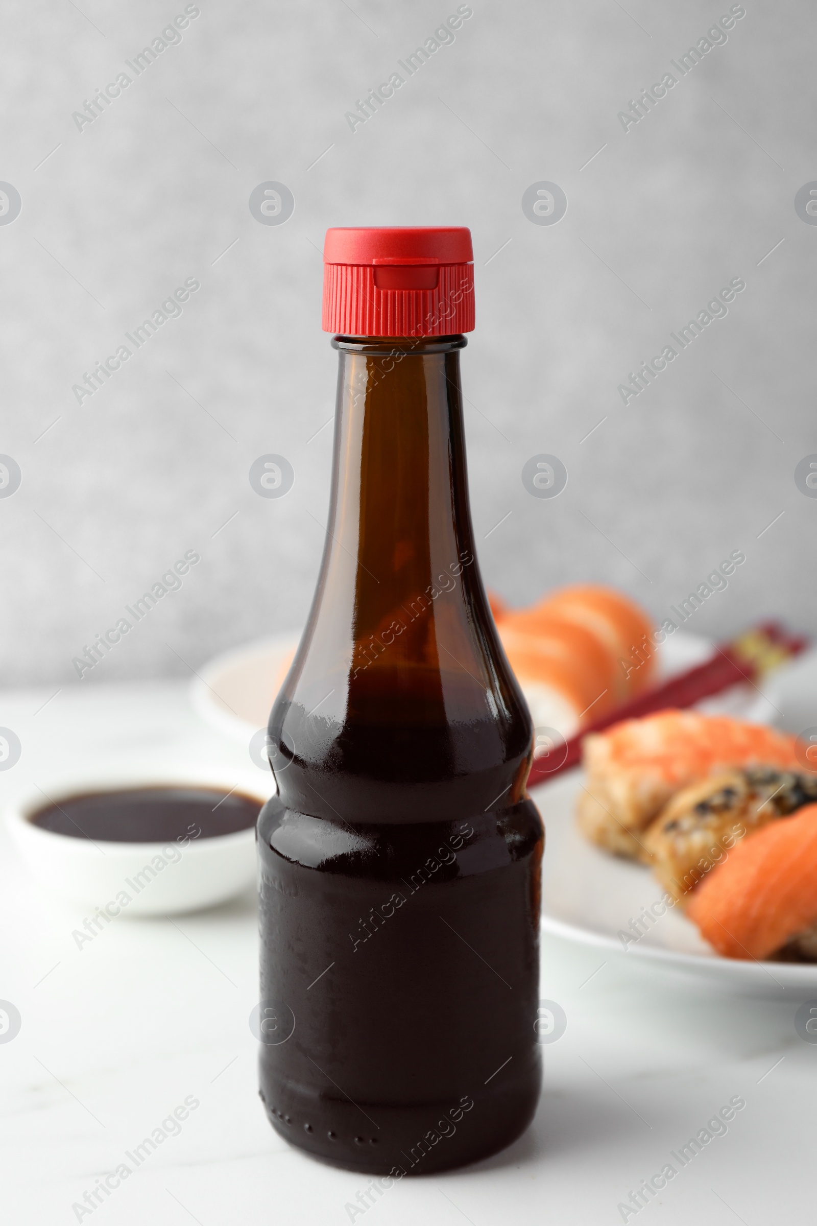 Photo of Tasty soy sauce and different types of sushi on white table