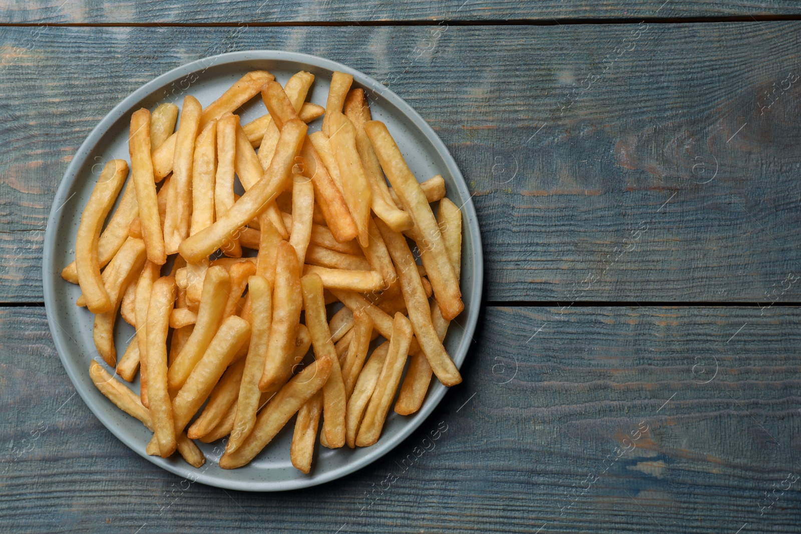 Photo of Tasty french fries on wooden table, top view. Space for text