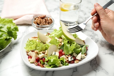 Photo of Woman with tasty pear salad at white marble table, closeup