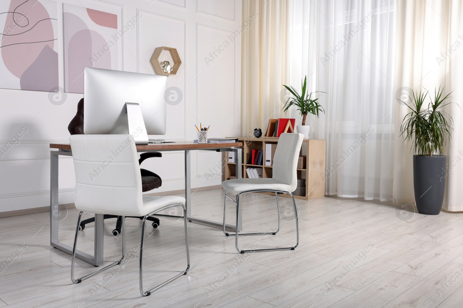 Photo of Director's workplace with wooden table, computer and comfortable armchairs. Interior design