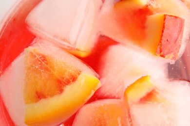 Tropical cocktail with ice cubes and orange pieces, top view