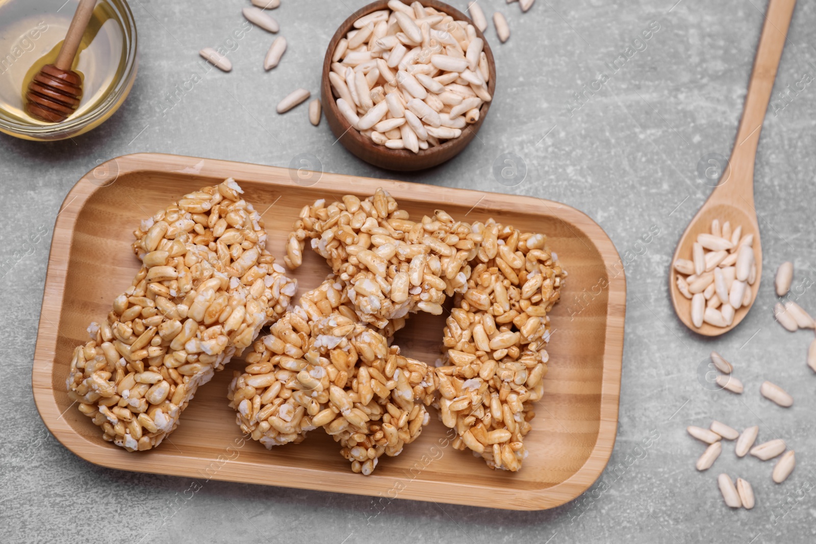 Photo of Plate with puffed rice pieces (kozinaki) on grey table, flat lay