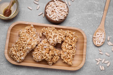 Plate with puffed rice pieces (kozinaki) on grey table, flat lay