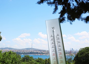 Weather thermometer and view of beautiful city and sea on background, space for text