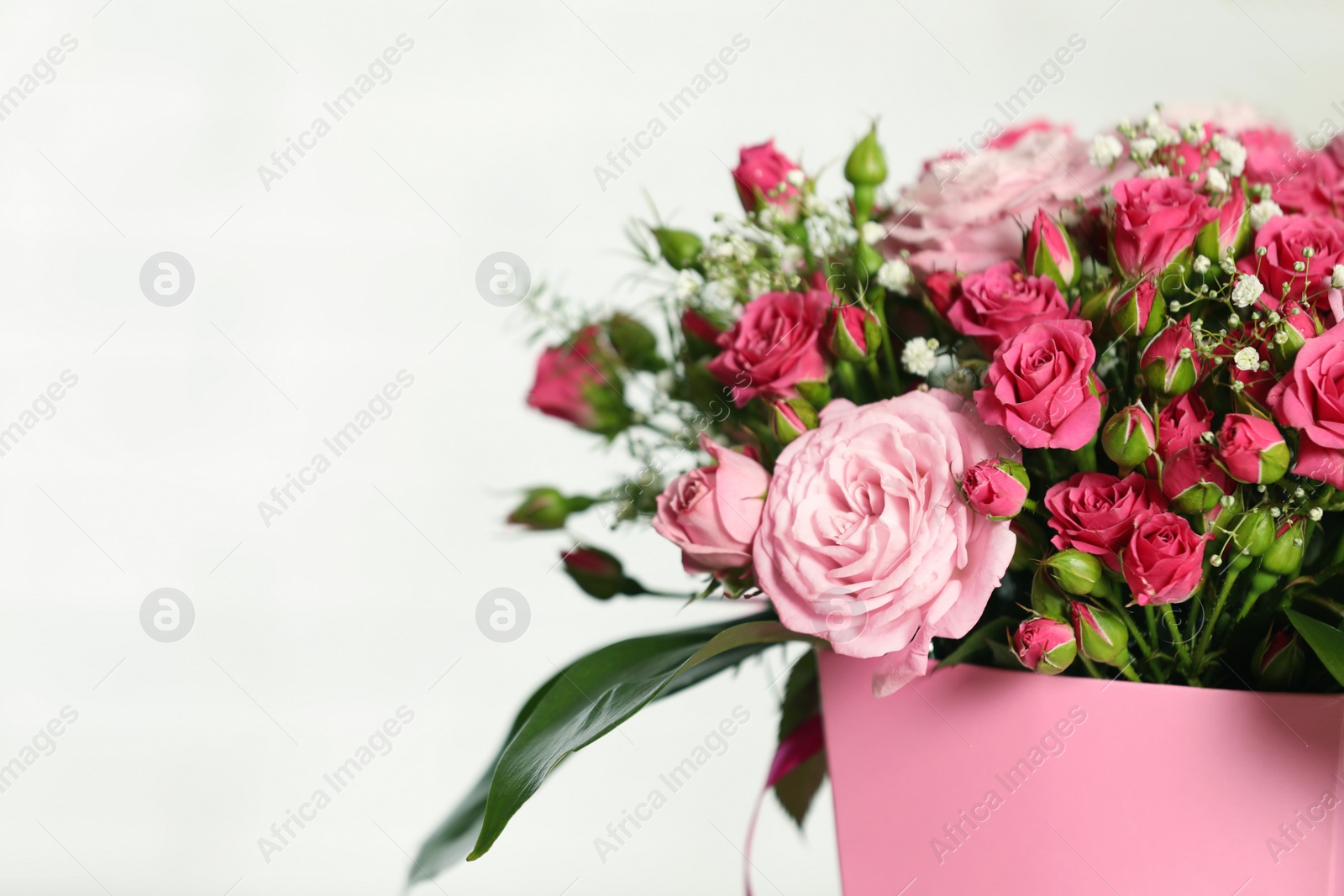 Photo of Beautiful bouquet of flowers in paper gift box on light background. Space for text