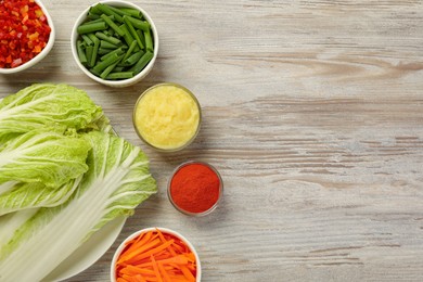 Photo of Fresh Chinese cabbages and other kimchi ingredients on wooden table, flat lay. Space for text