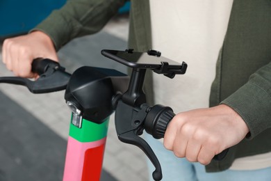 Man riding electric kick scooter with smartphone outdoors, closeup