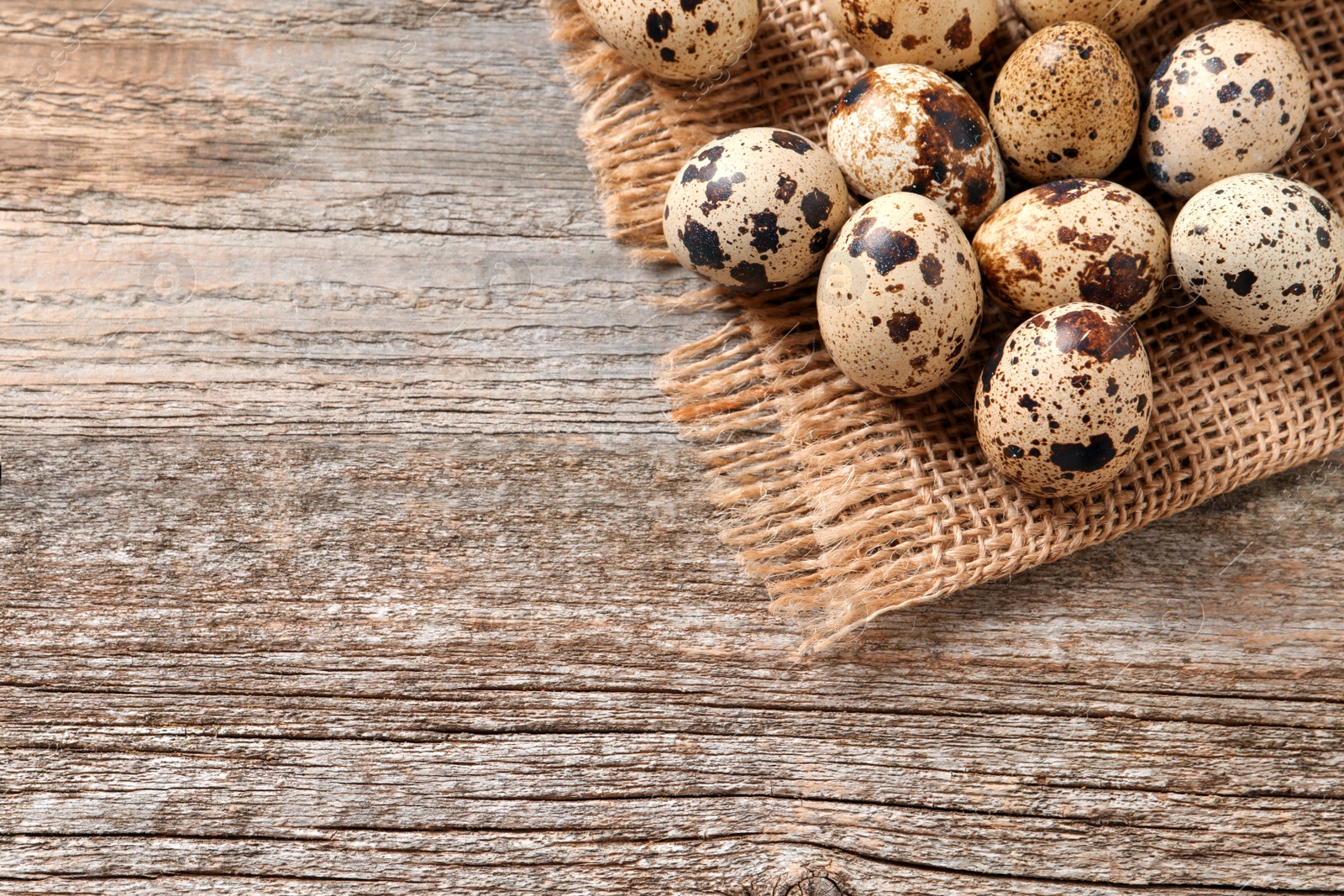 Photo of Fresh quail eggs on wooden table, top view. Space for text